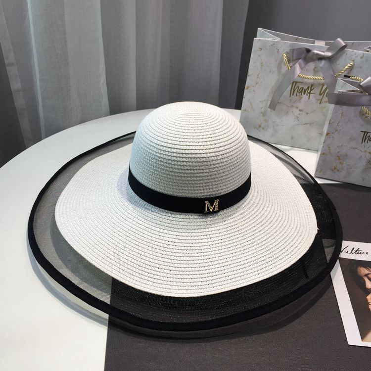 Skydd i Hepburn-stil, skuggning, barns mångsidiga sommarutflykt med stor brättad halm, solhatt, semester, vit strand_voghion.com