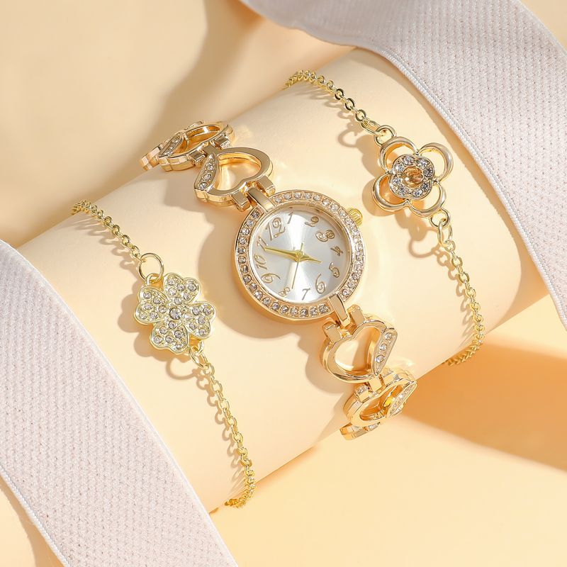 Orologio a forma di cuore con diamanti e bracciale a forma di quadrifoglio con fiore_voghion.com