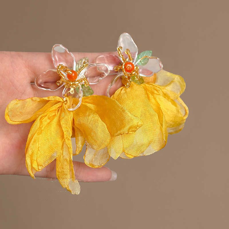 Orecchini a bottone con fiore in stile vacanza esagerato, con aghi d'argento e petali gialli, atmosfera da fata super, 2024._voghion.com