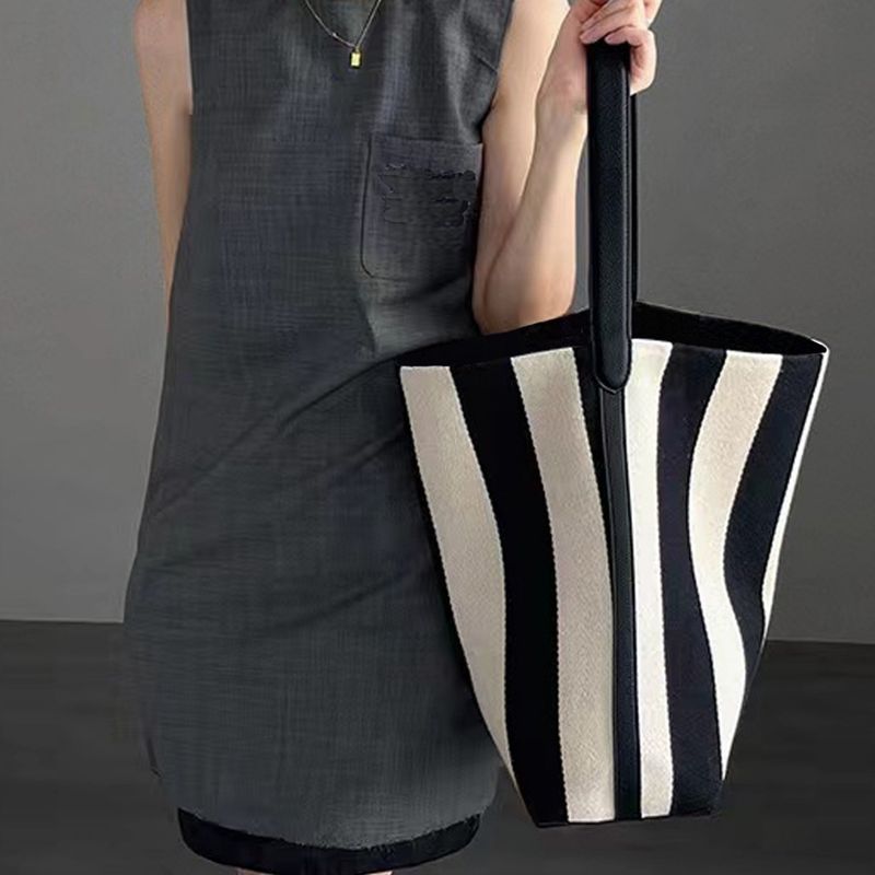 Borsa a secchiello grande capacità da donna con tracolla larga, in tela a righe, primavera estate 2025, in bianco e nero, con blocchi di colore_voghion.com