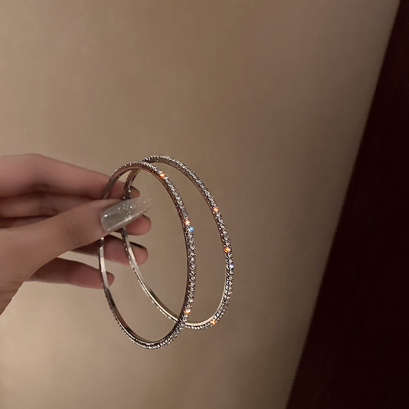 Orecchini pendenti alla moda ed eleganti con grandi cerchi tempestati di diamanti, esagerati in argento, per snellire il viso e dare personalità._voghion.com