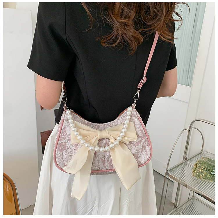 Il popolare fiocco di quest'anno per la primavera 2024 delle donne, la nuova borsa a tracolla singola sotto le ascelle con perle trendy e alla moda_voghion.com