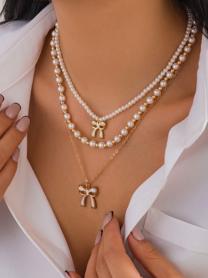Set di collane a strati con perle e fiocco per donna, collana multifilo in perle finte color oro con ciondolo a fiocco in smalto, gioielli eleganti di ispirazione vintage_voghion.com