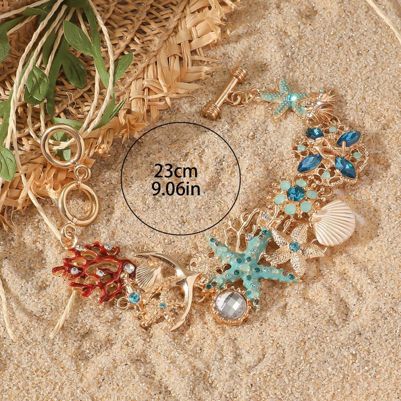 Braccialetto con ciondolo in metallo intarsiato di stelle marine, corallo, conchiglie e Oceano di Cayi Bohemian_voghion.com