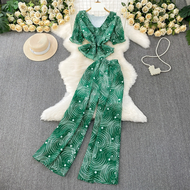 Completo leggero e maturo, snellente, composto da una maglietta a maniche corte con scollo a V e volant e pantaloni larghi e dritti in chiffon stampato a vita alta. Completo due pezzi._voghion.com