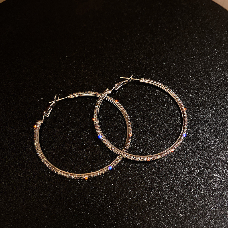 Orecchini pendenti alla moda ed eleganti con grandi cerchi tempestati di diamanti, esagerati in argento, per snellire il viso e dare personalità._voghion.com