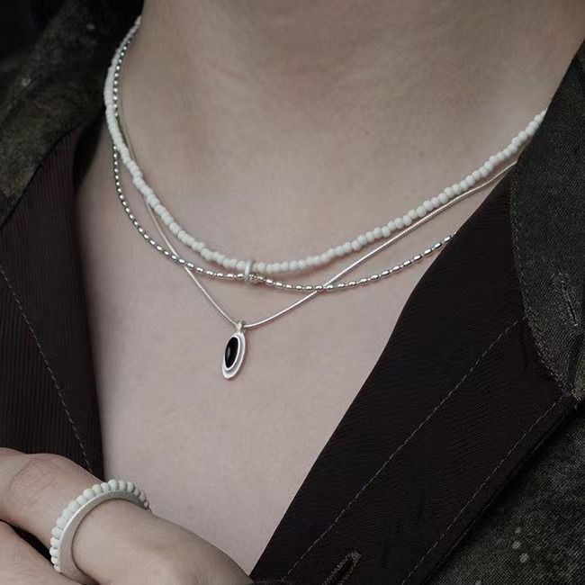 Il design della perlina rotonda in pietra di pino bianco a doppio strato in argento puro Same S di Dong Jie è semplice e realizzato a mano con un breve_voghion.com