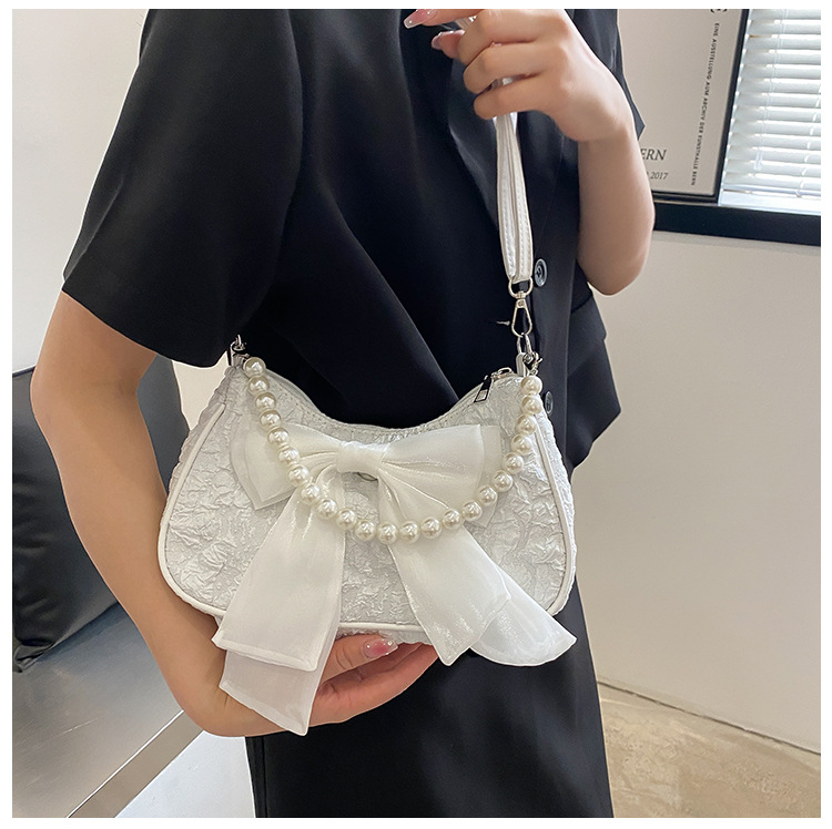 Il popolare fiocco di quest'anno per la primavera 2024 delle donne, la nuova borsa a tracolla singola sotto le ascelle con perle trendy e alla moda_voghion.com