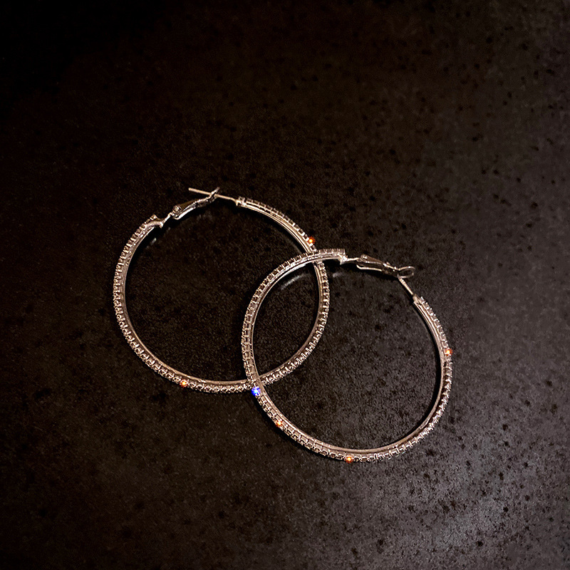 Orecchini pendenti alla moda ed eleganti con grandi cerchi tempestati di diamanti, esagerati in argento, per snellire il viso e dare personalità._voghion.com