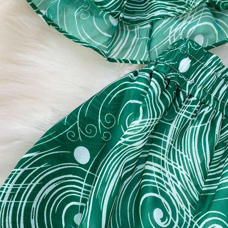 Completo leggero e maturo, snellente, composto da una maglietta a maniche corte con scollo a V e volant e pantaloni larghi e dritti in chiffon stampato a vita alta. Completo due pezzi._voghion.com