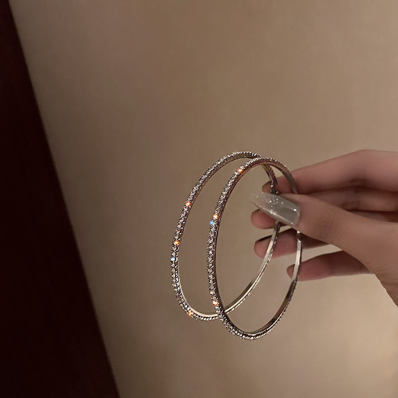 Orecchini pendenti alla moda ed eleganti con grandi cerchi tempestati di diamanti, esagerati in argento, per snellire il viso e dare personalità._voghion.com