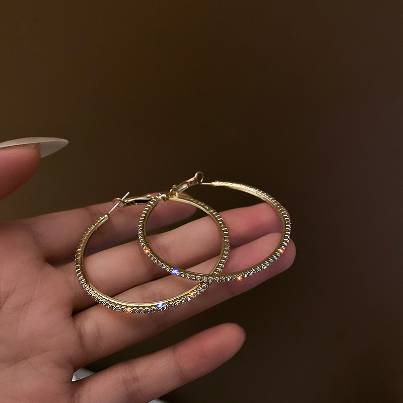 Orecchini pendenti alla moda ed eleganti con grandi cerchi tempestati di diamanti, esagerati in argento, per snellire il viso e dare personalità._voghion.com