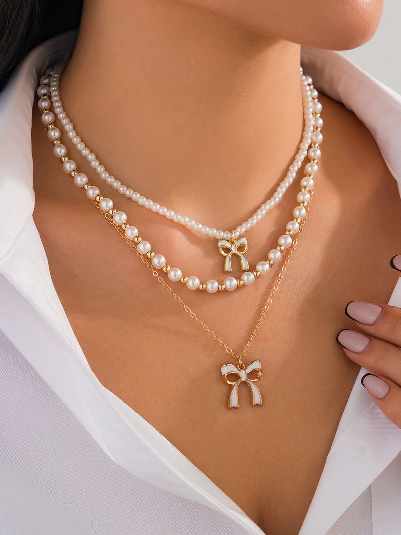Set di collane a strati con perle e fiocco per donna, collana multifilo in perle finte color oro con ciondolo a fiocco in smalto, gioielli eleganti di ispirazione vintage_voghion.com