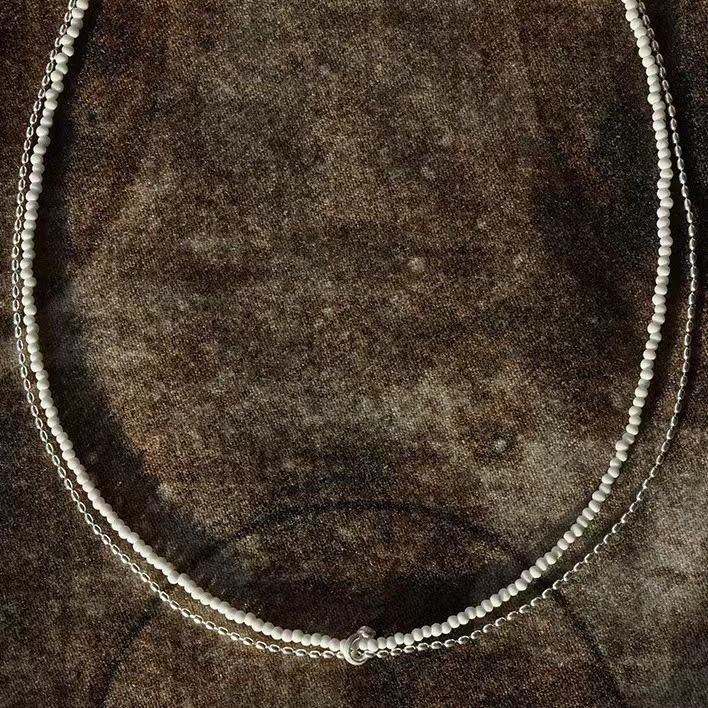 Il design della perlina rotonda in pietra di pino bianco a doppio strato in argento puro Same S di Dong Jie è semplice e realizzato a mano con un breve_voghion.com