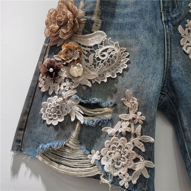 Pantaloncini in denim alla moda alla moda, con elastico in vita e strass sul retro, nuovi pantaloncini in pizzo con cuciture a fiori e fori estivi 2025_voghion.com